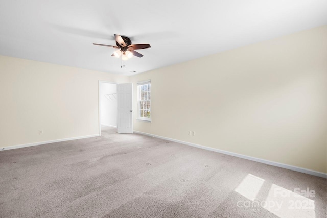 spare room with light colored carpet, baseboards, and ceiling fan