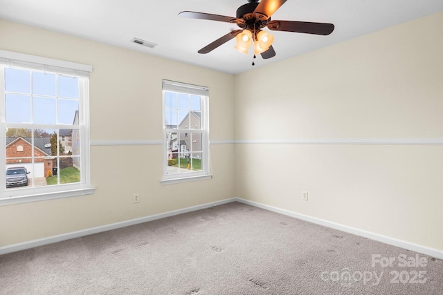 carpeted empty room with visible vents, baseboards, and a ceiling fan