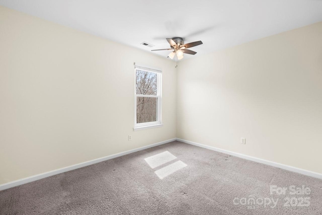 carpeted spare room featuring visible vents, baseboards, and ceiling fan