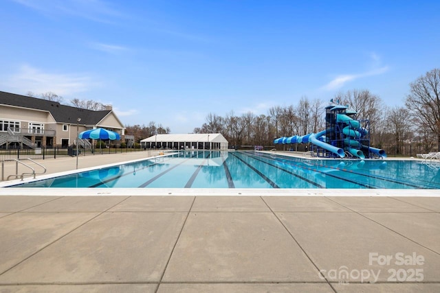 pool with a patio, a water slide, and fence