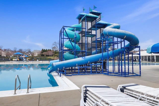 pool featuring fence, playground community, a water slide, and a water play area