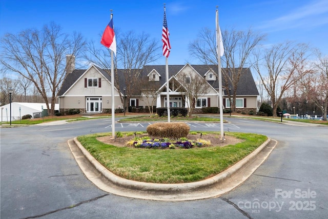 view of front of house featuring stone siding, uncovered parking, and a front lawn