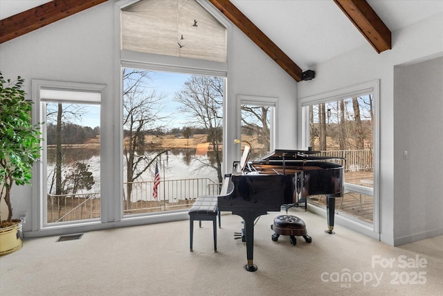 sitting room with beamed ceiling, carpet flooring, visible vents, and a water view