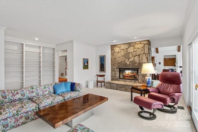 living area featuring built in shelves, ornamental molding, recessed lighting, carpet, and a stone fireplace