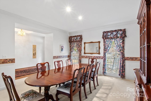 dining room with light carpet, wainscoting, and crown molding