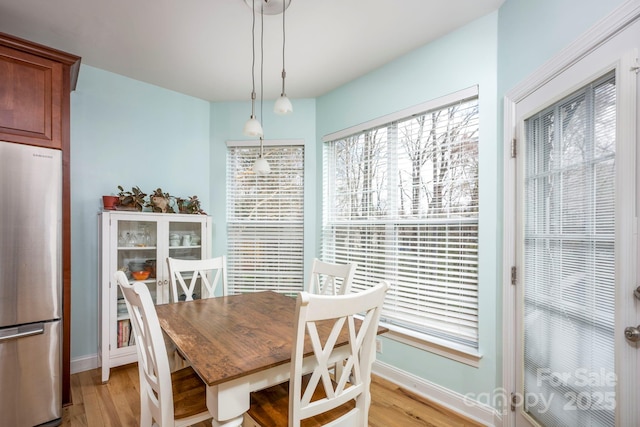 dining space featuring baseboards and light wood-style flooring