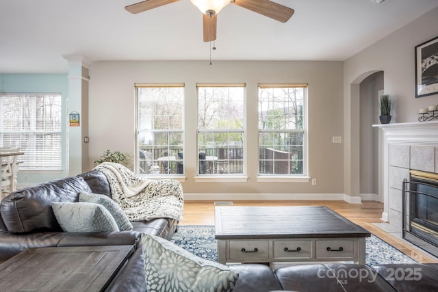 living area with light wood finished floors, visible vents, baseboards, ceiling fan, and a tile fireplace