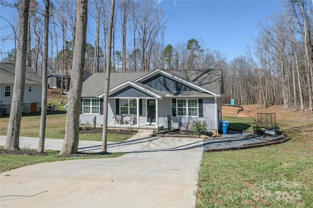 view of front of property with board and batten siding, covered porch, concrete driveway, and a front lawn