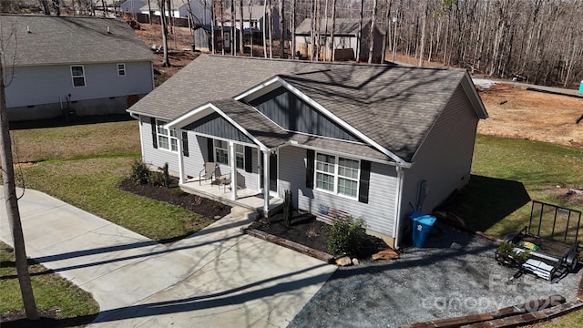 view of front of property featuring covered porch, a shingled roof, and a front yard