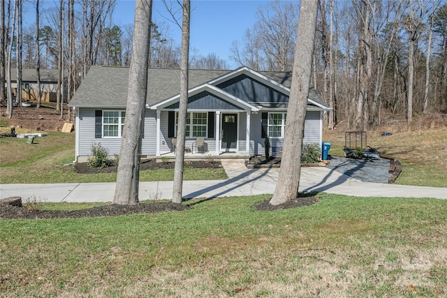 view of front of home featuring driveway, covered porch, a front yard, and a shingled roof