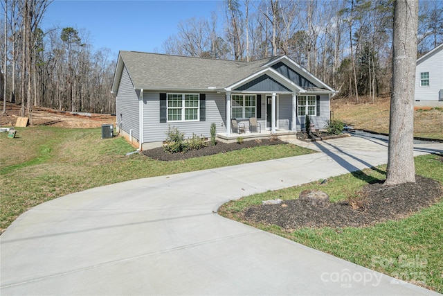 single story home featuring a porch, concrete driveway, a front yard, roof with shingles, and cooling unit