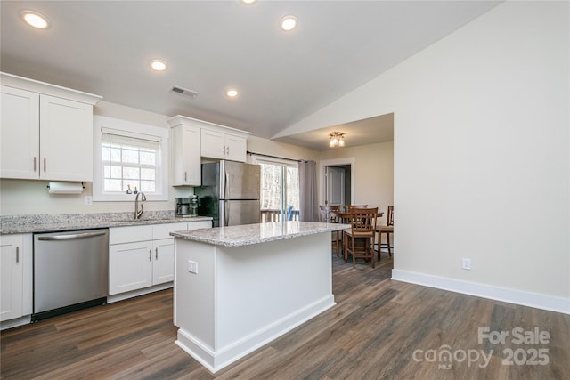 kitchen featuring visible vents, a kitchen island, a sink, white cabinets, and appliances with stainless steel finishes