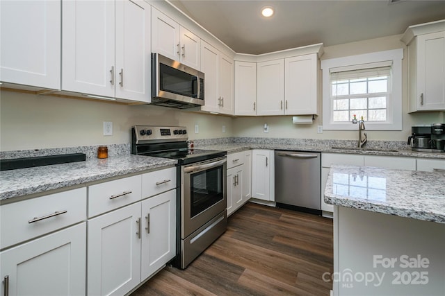 kitchen with white cabinets, appliances with stainless steel finishes, dark wood-type flooring, and a sink