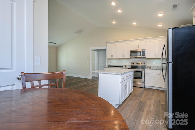 kitchen with dark wood finished floors, white cabinets, appliances with stainless steel finishes, and a kitchen island