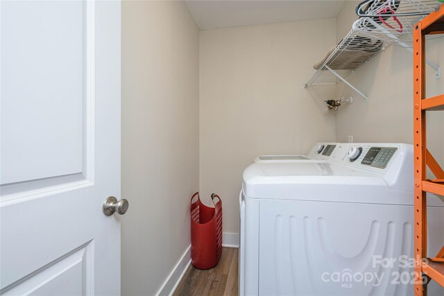 laundry room featuring laundry area, washing machine and dryer, baseboards, and wood finished floors