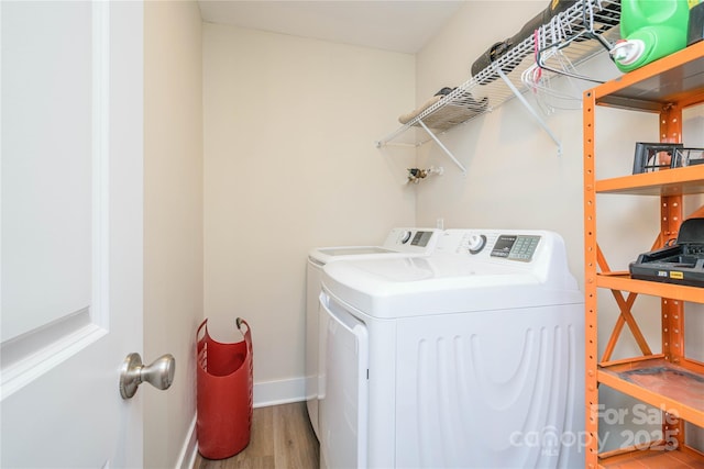 laundry room with laundry area, washer and dryer, baseboards, and wood finished floors