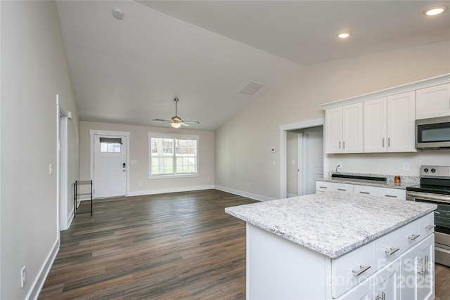 kitchen with a kitchen island, vaulted ceiling, stainless steel appliances, white cabinetry, and a ceiling fan