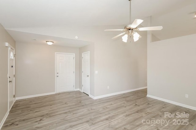 spare room with a ceiling fan, light wood-style floors, baseboards, and high vaulted ceiling