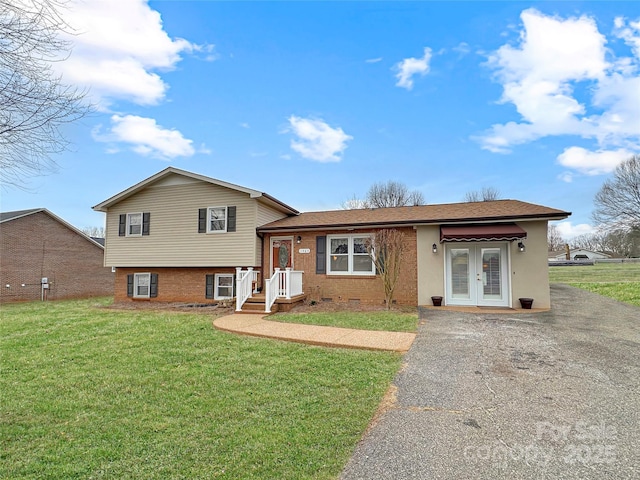 split level home featuring a front lawn, french doors, and driveway