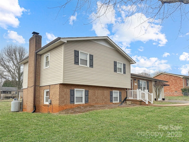 exterior space with brick siding, a chimney, a front yard, and fence