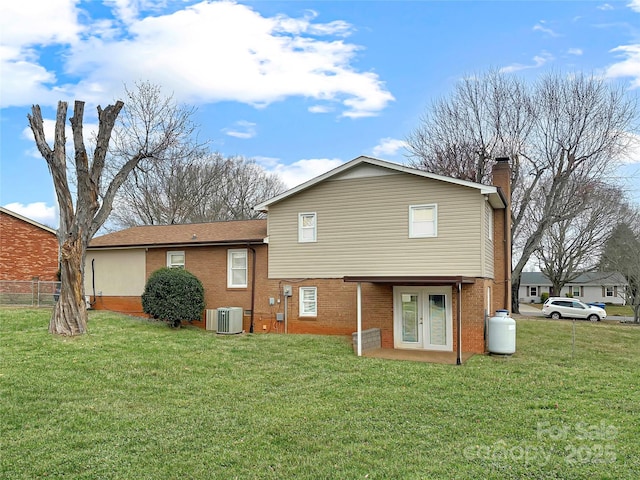 rear view of property with french doors, brick siding, central AC unit, and a chimney