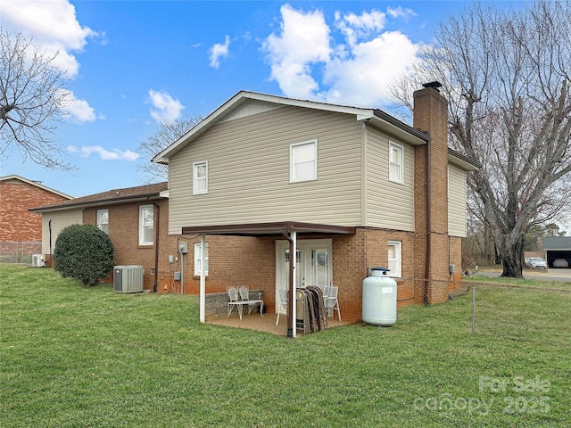 back of house featuring brick siding, central air condition unit, a lawn, and a patio