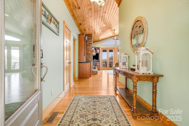 corridor with visible vents, light wood finished floors, lofted ceiling, french doors, and wooden ceiling