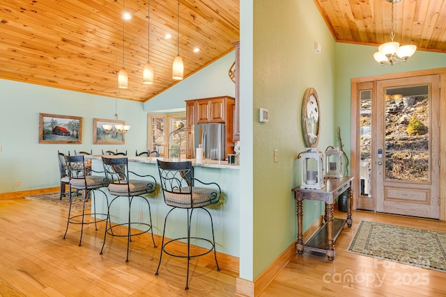 interior space featuring wood ceiling, a kitchen bar, an inviting chandelier, and freestanding refrigerator