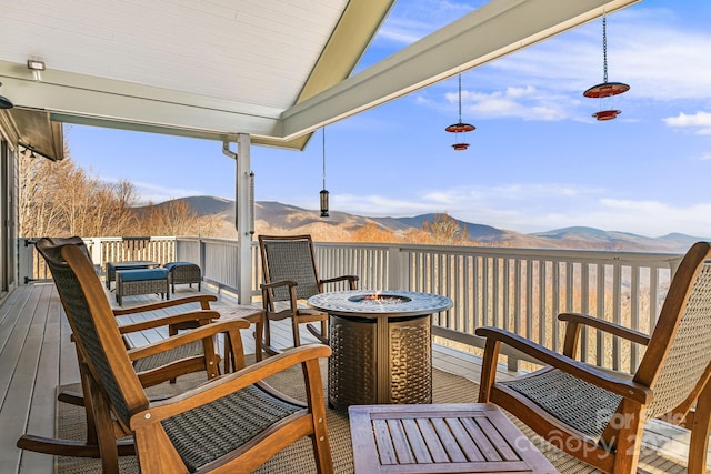 wooden deck featuring a mountain view and an outdoor fire pit