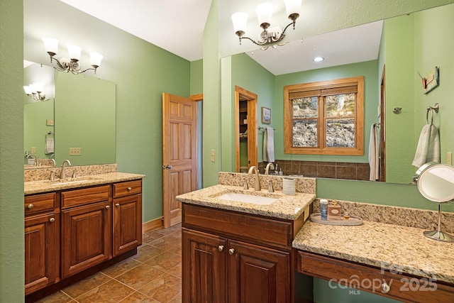 bathroom with two vanities, a notable chandelier, and a sink