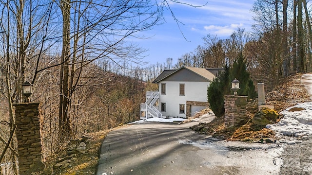 view of side of home with aphalt driveway and stairs