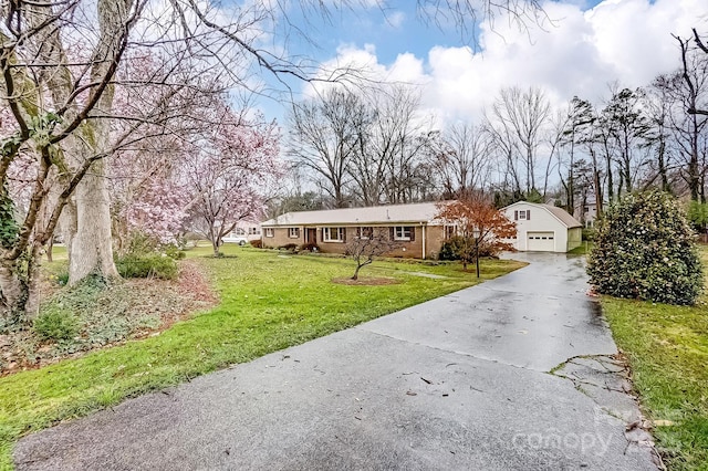 ranch-style house with aphalt driveway, brick siding, a detached garage, and a front yard