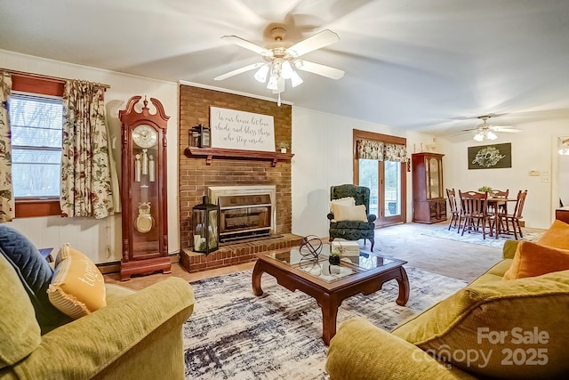 carpeted living room with a brick fireplace, ceiling fan, and a baseboard radiator