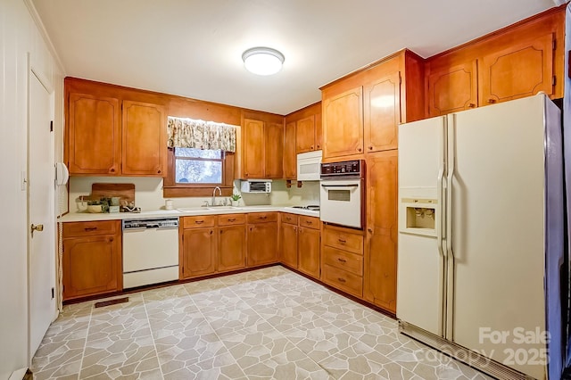 kitchen featuring visible vents, white appliances, light countertops, and a sink