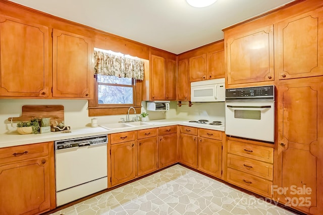 kitchen featuring a sink, white appliances, brown cabinets, and light countertops