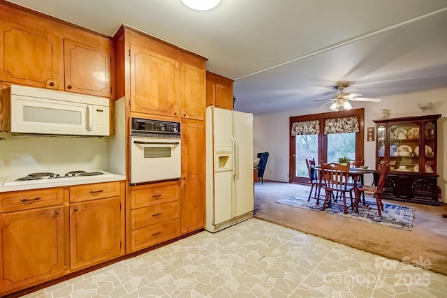 kitchen with light carpet, brown cabinets, white appliances, and light countertops