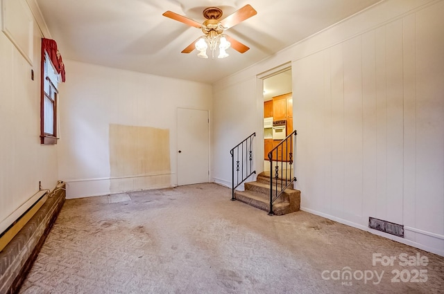 spare room featuring a baseboard radiator, a ceiling fan, carpet flooring, and stairway