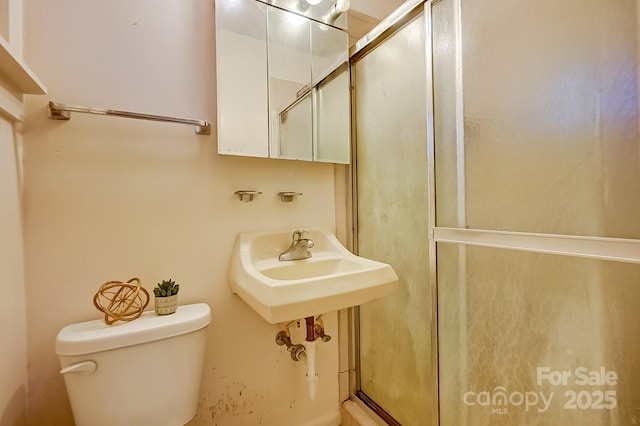 bathroom featuring toilet and a shower with shower door