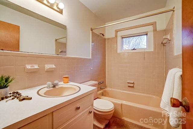 bathroom featuring vanity, toilet, tile walls, and washtub / shower combination