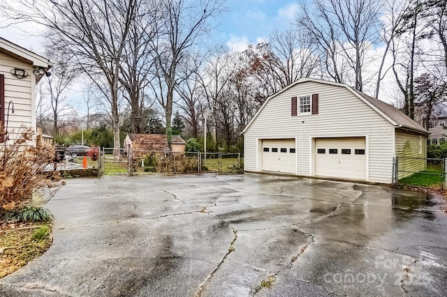 garage featuring fence, a detached garage, and a gate