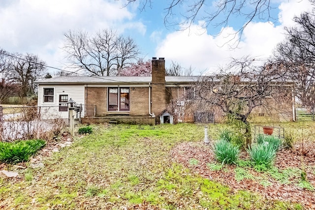 back of house featuring a yard, fence, brick siding, and a chimney