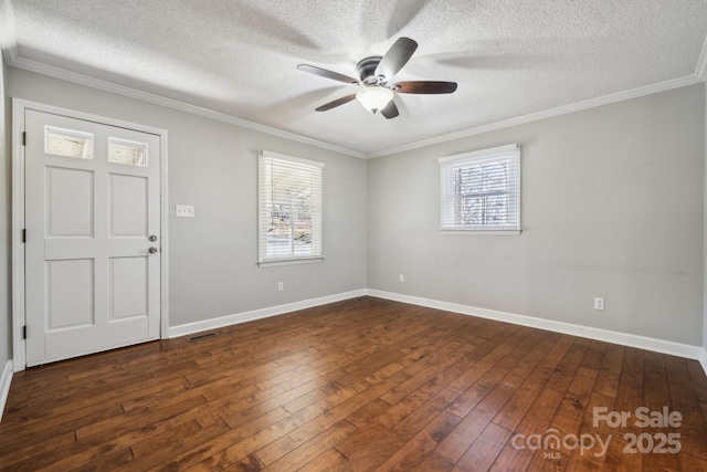 empty room with a ceiling fan, dark wood-type flooring, crown molding, and baseboards