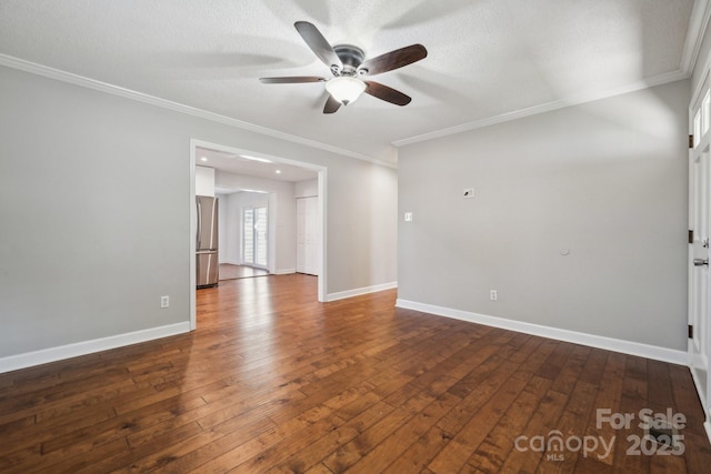 empty room with a textured ceiling, crown molding, baseboards, and dark wood-style flooring