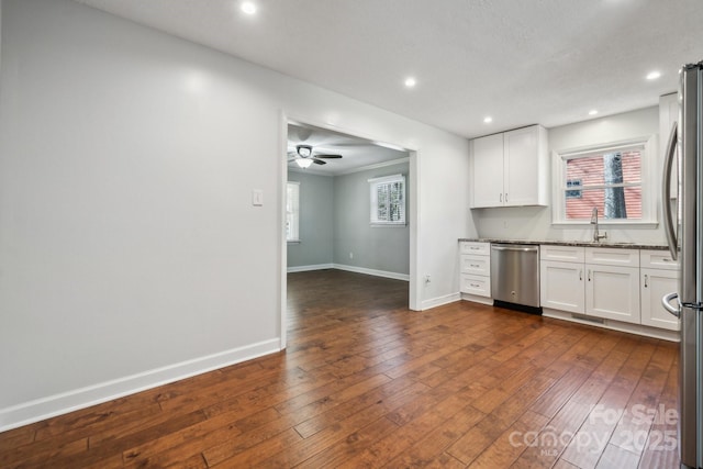 kitchen featuring baseboards, a sink, dark wood-type flooring, white cabinets, and appliances with stainless steel finishes