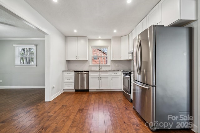 kitchen with dark wood finished floors, white cabinets, baseboards, and stainless steel appliances