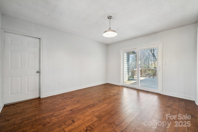 spare room featuring dark wood-style floors, baseboards, and a textured ceiling