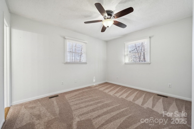 unfurnished room with visible vents, baseboards, a textured ceiling, and carpet flooring