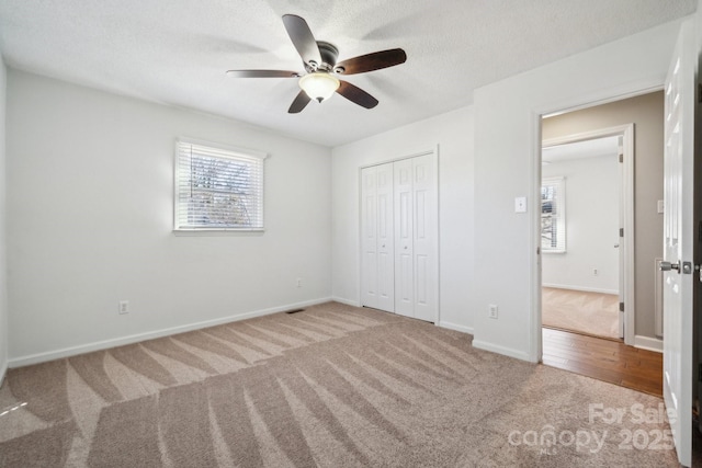 unfurnished bedroom featuring baseboards, carpet floors, ceiling fan, a closet, and a textured ceiling