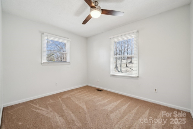 empty room featuring carpet flooring, baseboards, visible vents, and ceiling fan