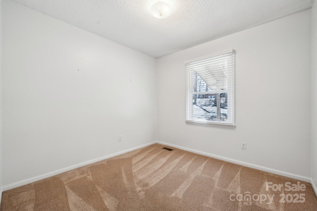 carpeted empty room featuring visible vents, a textured ceiling, and baseboards